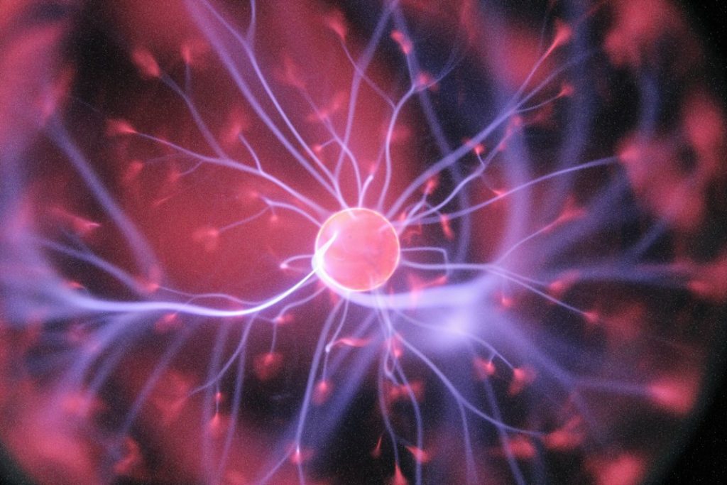 A glowing plasma ball with purple and pink light filaments radiating from its centre, set against a dark background, illustrating electric energy or scientific phenomena.