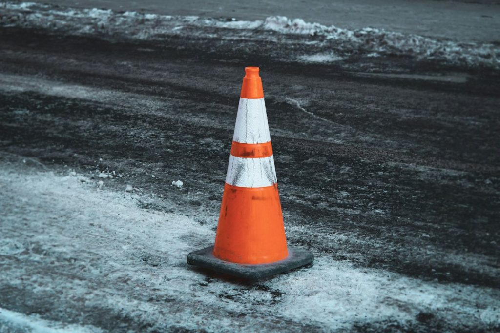 An orange and white cone on a road.